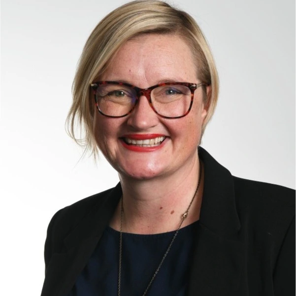 lady with blond hair, wearing glasses, smiling at the camera in a protrait shot